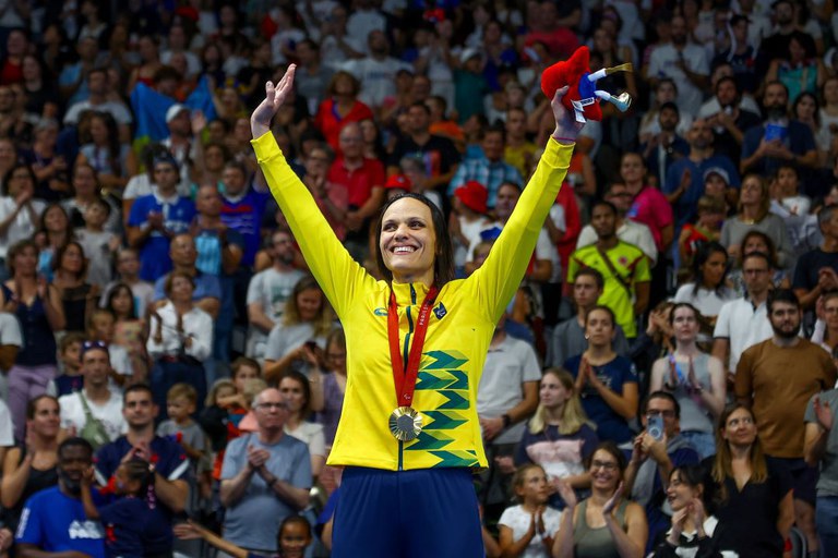 A nadadora Carol Santiago com os braços pra cima comemorando a quarta medalha de ouro.